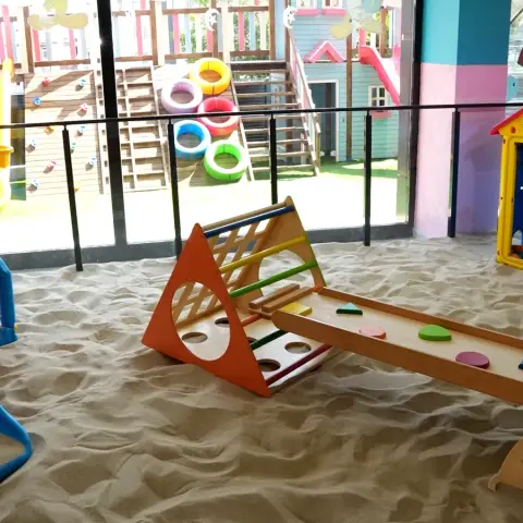 Kum havuzunda ahşap tırmanma seti, arkada bahçe